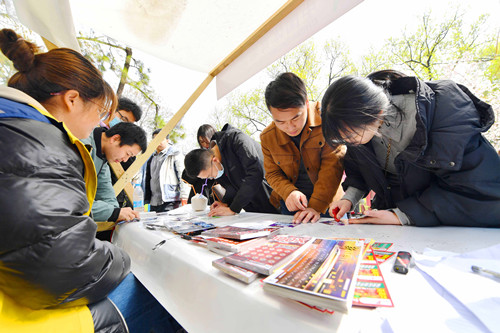 年轻人在南京玄武湖樱花节现场体验体彩即开票_副本.jpg